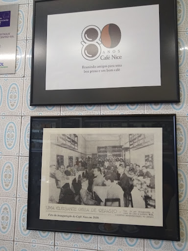 Duas molduras na parede de azulejos: o cartaz comemorativo dos 80 anos do Café Nice e, abaixo, uma fotografia antiga em preto e branco com a legenda Foto da inauguração do Café Nice em 1939.
